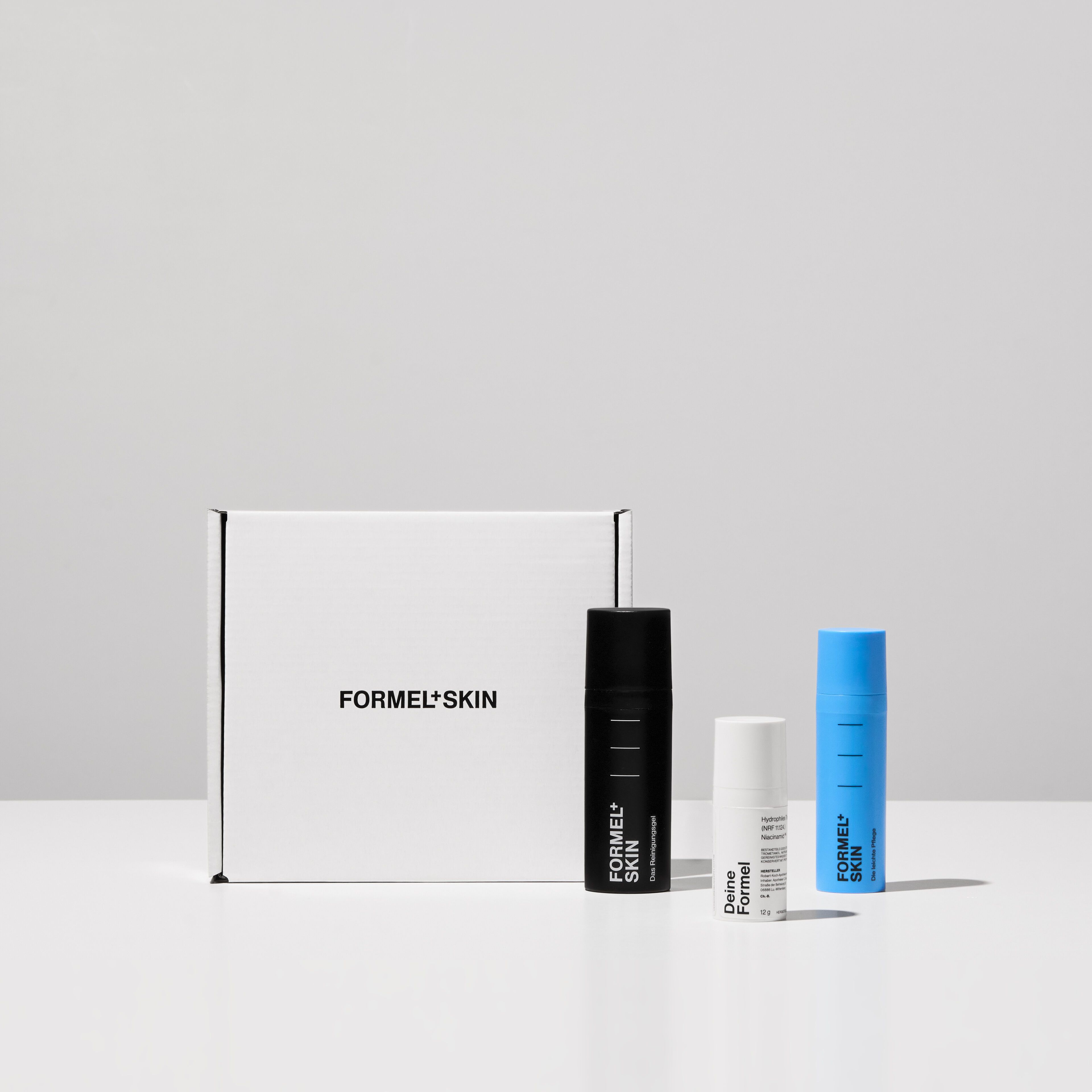 Three skincare products and a white box set against a grey background