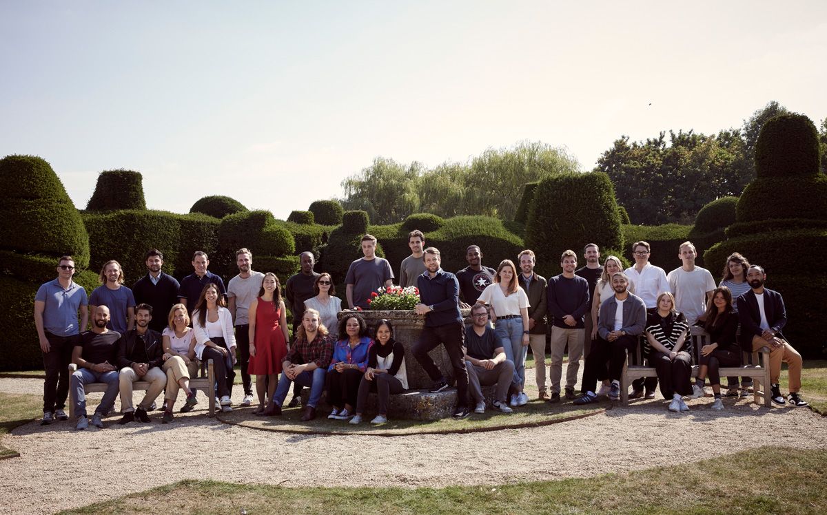 Large team of people posed in a garden