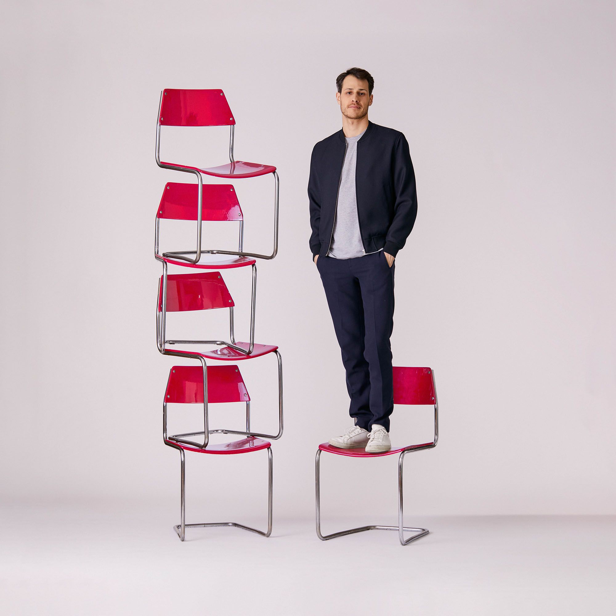 A man standing on a red chair.