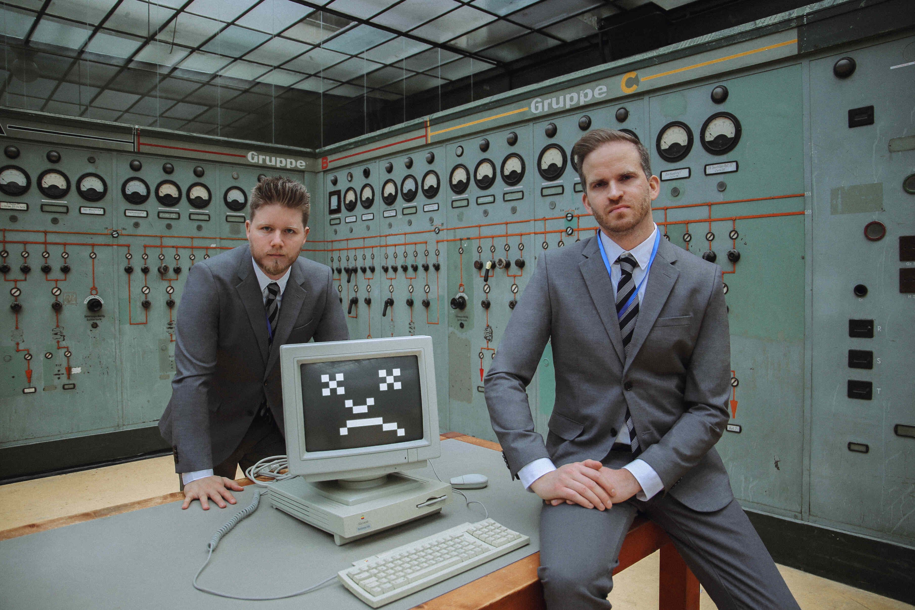 Two men in grey suits in a operating room with a computer between them