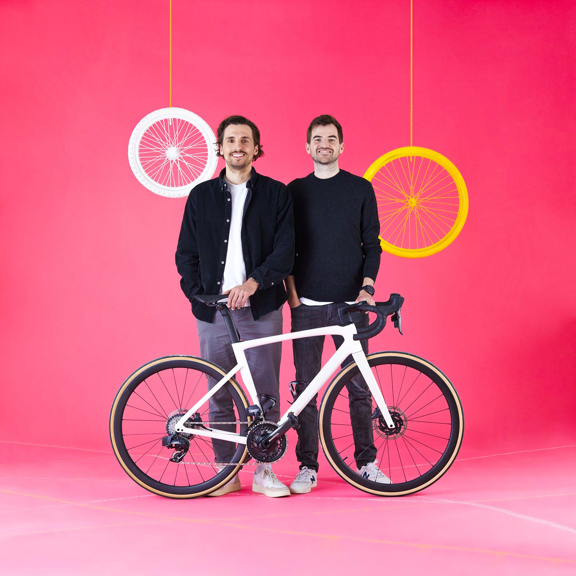 Three smiling men standing behind a bicycle