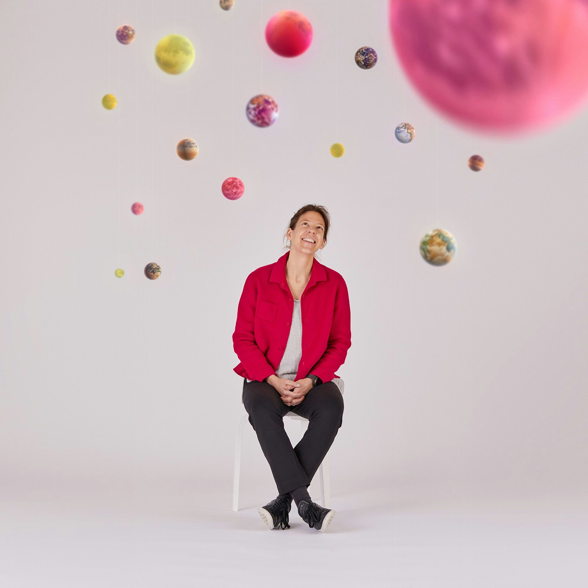 Woman sitting in a chair looking at planets hung from the ceiling