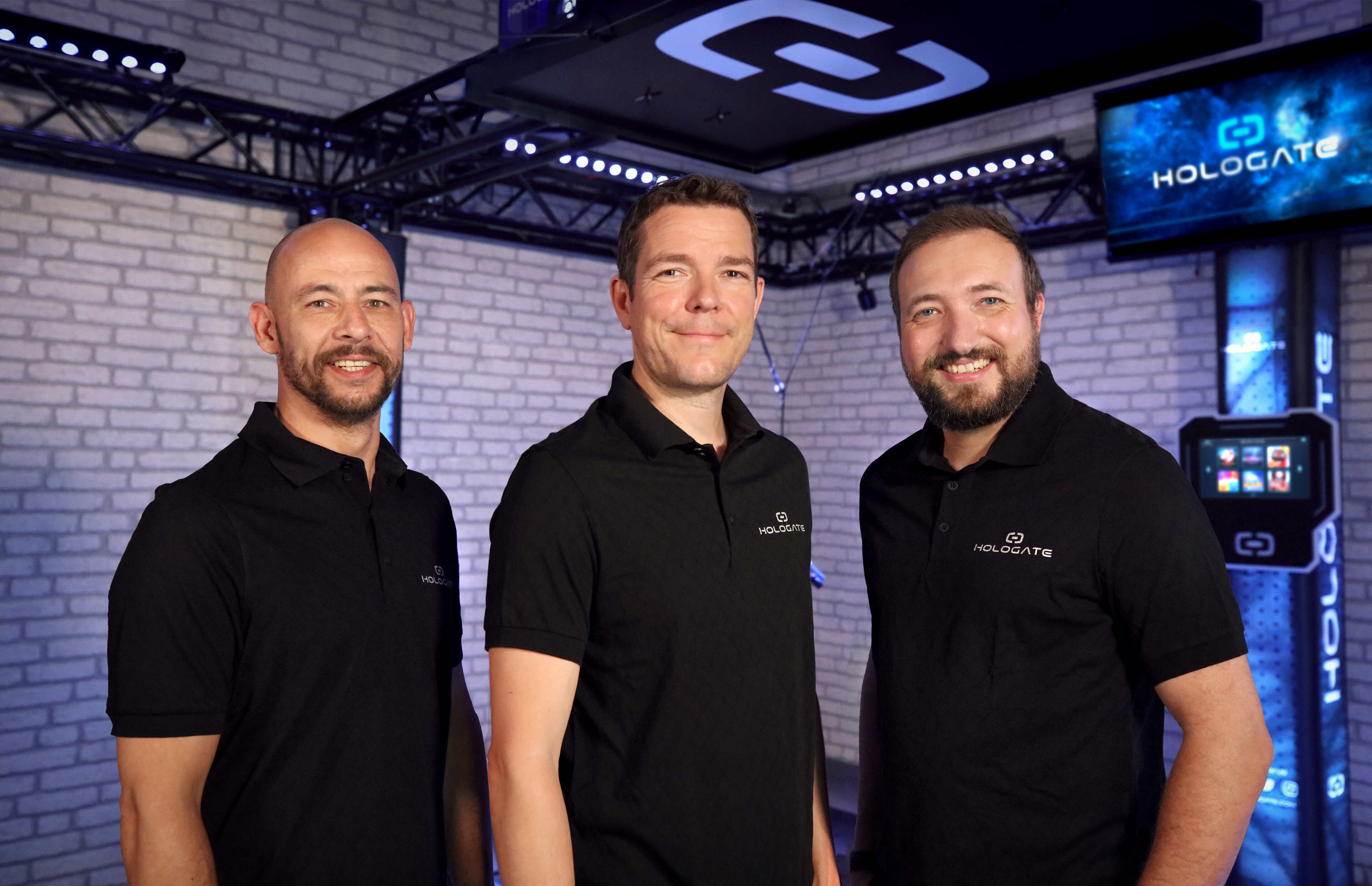 Thee men in black t-shirts smiling at the camera