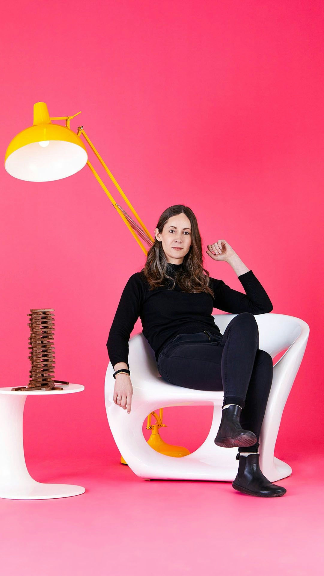Woman sitting in a chair in front of a pink background