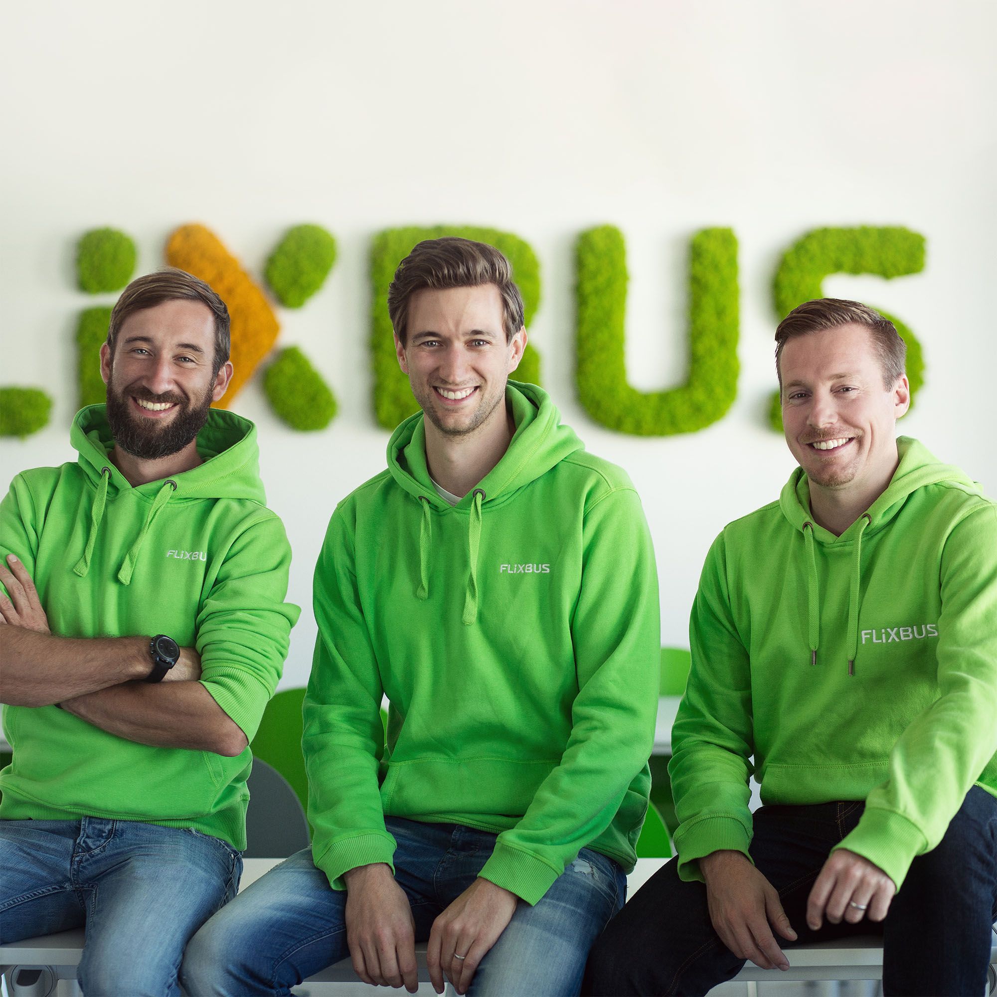 Green Flixbus train on a railway track in the middle of a green field